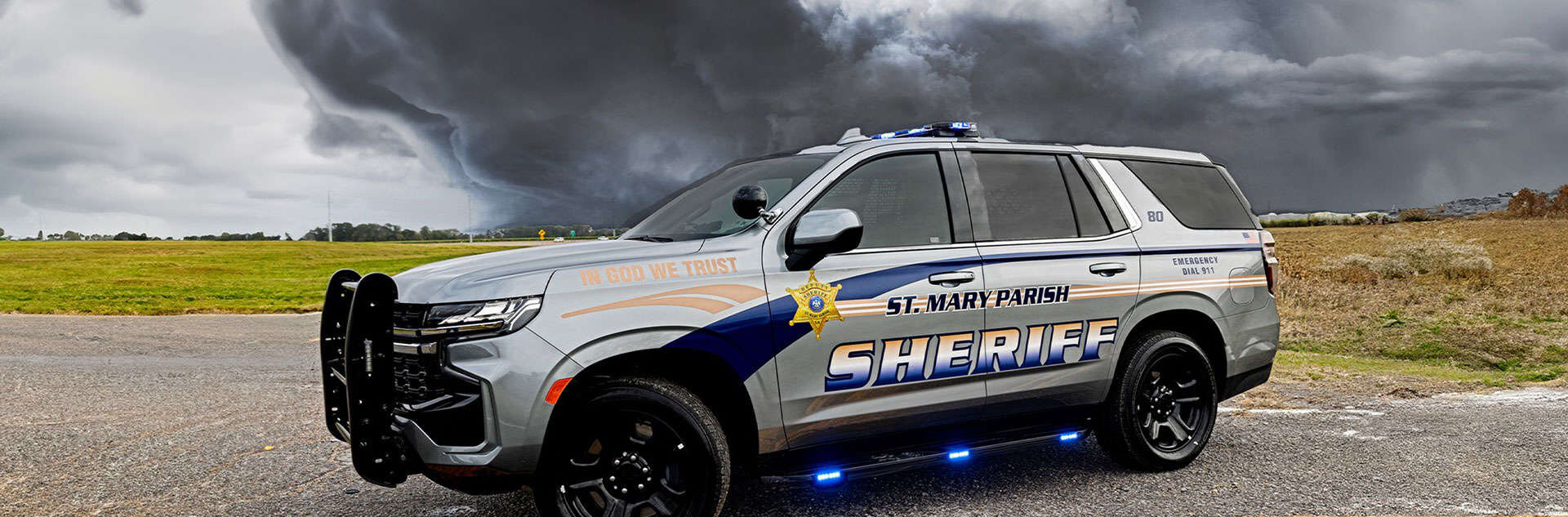 Sheriff patrol SUV in front of a dark thunderstorm cloud.